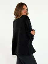 Sweater de punto color bordó, con cuello redondo, mangas largas abullonadas y detalle de flecos en las costuras de los hombros.