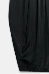 Pantalón bombacho negro confeccionado en tejido satinado, de tiro medio con cintura elástica y diseño con pliegues.