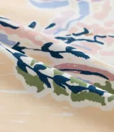 Remera de algodón color blanco crudo, manga corta y cuello redondo, con un pequeño estampado floral y lettering en el área del pecho.