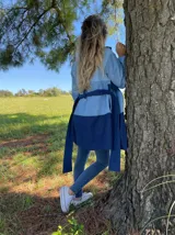 Tapado de jean con diseño color block en dos tonos de azul, con cuello solapa y lazo para atar en la cintura.