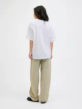 Remera de cuello redondo y mangas cortas, con calce holgado y estampa frontal de cerezas con texto decorativo.