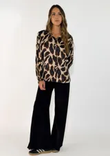 Camisa de manga larga con cuello camisero y cierre frontal de botones, confeccionada en tela fluida con estampado animal print en tonos marrones y negros.