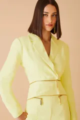 Blazer color amarillo con doble cierre dorado en la parte inferior.