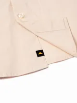 Camisa de manga larga Caterpillar estilo utilitario, color beige, con múltiples bolsillos con solapa en el pecho, detalles de tiras negras y logo de la marca bordado.