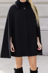 Capa negra de paño de lana con cuello de piel sintética y cierre con botón.