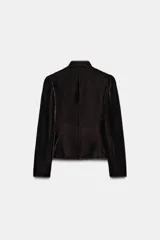 Blazer de terciopelo en color rosado con cuello subido y manga larga. Presenta cierre frontal con botones forrados y detalles de vivo en color oscuro a contraste en los bordes, cuello y puños. Incluye bolsillos delanteros de vivo.