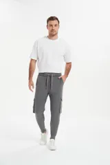 Babucha de estilo cargo en color gris, con cintura elástica ajustable mediante cordón, bolsillos laterales con solapa y puños elásticos en los tobillos.