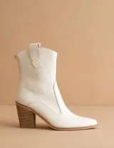 Bota texana de caña media color blanco, con taco cuadrado de madera y punta ligeramente afinada. Presenta un diseño minimalista con cierre posterior y tiradores laterales.