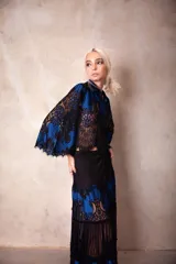 Camisa corta de encaje negro con base en color azul eléctrico, de corte holgado y mangas 3/4 con diseño acampanado.