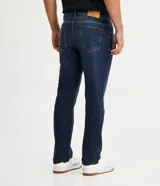 Pantalón de jean corte slim, color azul oscuro, con cierre frontal de botones y cremallera, bolsillos laterales y trabillas para cinturón.