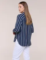 Camisa de crepe blanca con rayas verticales negras, cuello camisero, mangas largas raglán y cierre frontal con botones.