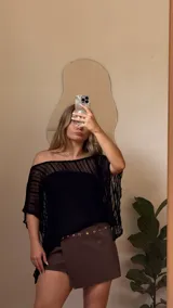 Capa de hilo negra con diseño de hombros descubiertos, mangas anchas y acampanadas, y textura de rayas verticales.