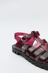 Sandalias jelly color gris translúcido, con diseño entrecruzado y hebilla lateral ajustable.