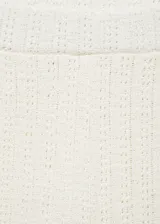 Pantalon de crochet color crema, de corte recto y tiro alto con cintura elástica. Presenta un diseño de tejido calado con aberturas laterales en el bajo.