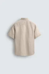 Camisa de lino color beige de corte relajado, con cuello solapa, manga corta y cierre frontal con botones.