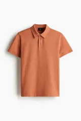 Remera polo de manga corta en punto de algodón liviano, color terracota, con cuello y tapeta de botones. Presenta un corte ajustado al cuerpo.