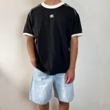 Remera de corte regular color blanco con detalles en gris oscuro en el cuello y los bordes de las mangas. Presenta un estampado pequeño centrado en el pecho.
