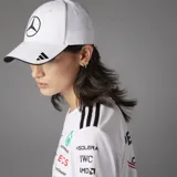 Gorro Adidas blanco con logo de Mercedes Benz bordado en negro en el frente y logo de Adidas bordado en negro en la visera.