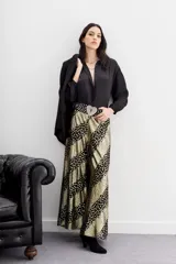 Pantalón de corte amplio y fluido, confeccionado en viscosa jacquard con hilos de lurex. Presenta un diseño de rayas diagonales con estampado de puntos dorados sobre fondo negro, cintura con elástico en la parte trasera y forrería a tono.