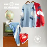 Buzo de algodón con diseño inspirado en la indumentaria deportiva uruguaya de 1995. Presenta un diseño de bloques de color con franjas diagonales en contraste, cuello redondo y bordado en el pecho. Cuenta con puños y cintura acanalados.