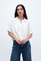 Blusa verde de manga corta con escote en V, cuello camisero y bolsillos en el pecho.