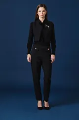Pantalon de vestir color verde oscuro, de corte recto y tiro alto. Presenta dos solapas decorativas en la cintura con apliques de broches metálicos con forma de insectos.