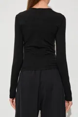 Remera Diesel de manga larga y corte ceñido al cuerpo, de color negro, con cuello redondo y el logotipo metálico ovalado de la marca en el centro del pecho.