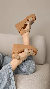 Sandalias de plataforma corrida color beige, con capellada de cuero y tira ajustable con hebilla en el tobillo.