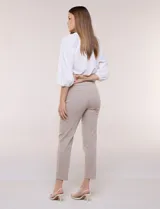 Pantalón de gabardina elastizada color beige, de tiro medio y calce slim. Cuenta con diseño pull-on sin cierres ni botones, cintura ancha, bolsillos delanteros simulados y bolsillos traseros ojal.