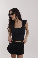 Blusa negra con escote cuadrado, breteles anchos con volados y corte a la cintura.