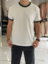 Remera oversize de algodón pesado en color blanco, con cuello redondo y ribetes en las mangas de color verde oscuro.