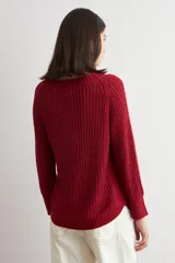 Sweater de punto con textura jaspeada en tonos marrones, de corte recto, cuello redondo y mangas largas. Presenta un diseño con ruedo curvo.