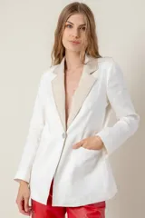 Blazer azul de lino con corte entallado, cuello y solapas combinadas en color gris, cierre con botón de nácar, bolsillos laterales y tajo en la espalda.