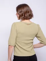 Top de manga tres cuartos color verde oliva, con cuello redondo y tejido texturizado. Las mangas son ligeramente abullonadas.