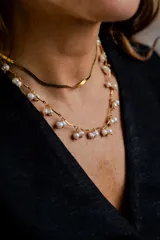 Collar de cadena dorada con diseño de eslabones curvos y perlas naturales colgantes distribuidas a lo largo de toda la pieza.