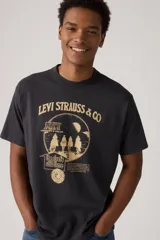 Remera negra de corte holgado con estampado gráfico vintage en color dorado. El diseño incluye el texto "Levi Strauss & Co", "Levi's for wear fit comfort & value", la silueta de cuatro jinetes a caballo, y el lema "the rivet's still there".