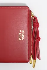 Billetera pequeña de estructura rígida, color negro, con estampado frontal en color dorado con la palabra "BIMBA". Posee cierre superior con tirador de tela amarillo mostaza.