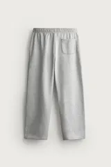 Pantalón jogger de corte relajado y pernera ancha, confeccionado en tejido de algodón con interior perchado. Cuenta con cintura elástica ajustable mediante cordón interior, bolsillos laterales y un bolsillo trasero de plastrón.
