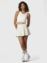 Falda skort deportiva de tiro alto, color blanco con borde inferior en contraste negro. Incluye short integrado con bolsillo lateral.