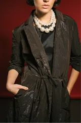 Tapado largo de tela tornasolada que combina tonos gris, marrón y azul. Tiene corte recto, mangas amplias y forro completo.