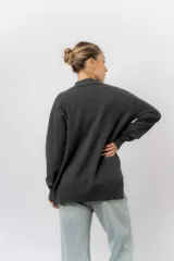 Sweater de tejido de punto color marrón, con cuello alto, corte relajado y terminaciones en rib en puños y cintura. Presenta una hilera de botones metálicos decorativos en uno de los laterales.