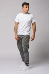 Pantalón cargo color beige de gabardina, con corte ajustado, bolsillos laterales con fuelle y puños elásticos en los tobillos.