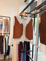 Chaleco artesanal confeccionado en cuero, con diseño de cordones decorativos en el frente y terminaciones rústicas.