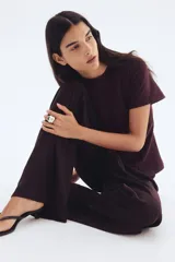 Top de manga corta color borgoña, con cuello redondo y corte entallado que se acampana ligeramente hacia el bajo gracias a las pinzas moldeadoras frontales.