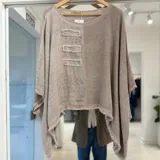 Blusa de lino color visón, de corte asimétrico y holgado, con cuello redondo y detalles de parches rectangulares desmechados en el frente.