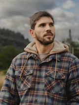Camisa overshirt de franela a cuadros con interior de chiporro, cierre frontal con botones, bolsillos en el pecho y capucha integrada.
