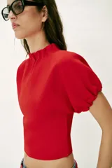 Top de punto color azul marino, con cuello redondo y mangas cortas abullonadas con acabados elásticos fruncidos.