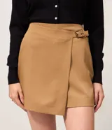 Short pollera de sastrería color marrón, confeccionado en mezcla de poliéster y viscosa, con diseño cruzado tipo envolvente.