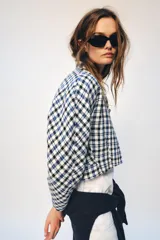 Chaqueta corta de Zara Woman Collection confeccionada en tejido de algodón con estampado de cuadros en tonos blanco, azul y negro. Presenta escote en pico, manga larga y cierre frontal con botones oscuros.