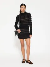 Minivestido negro con cuello alto, mangas largas y volados horizontales.